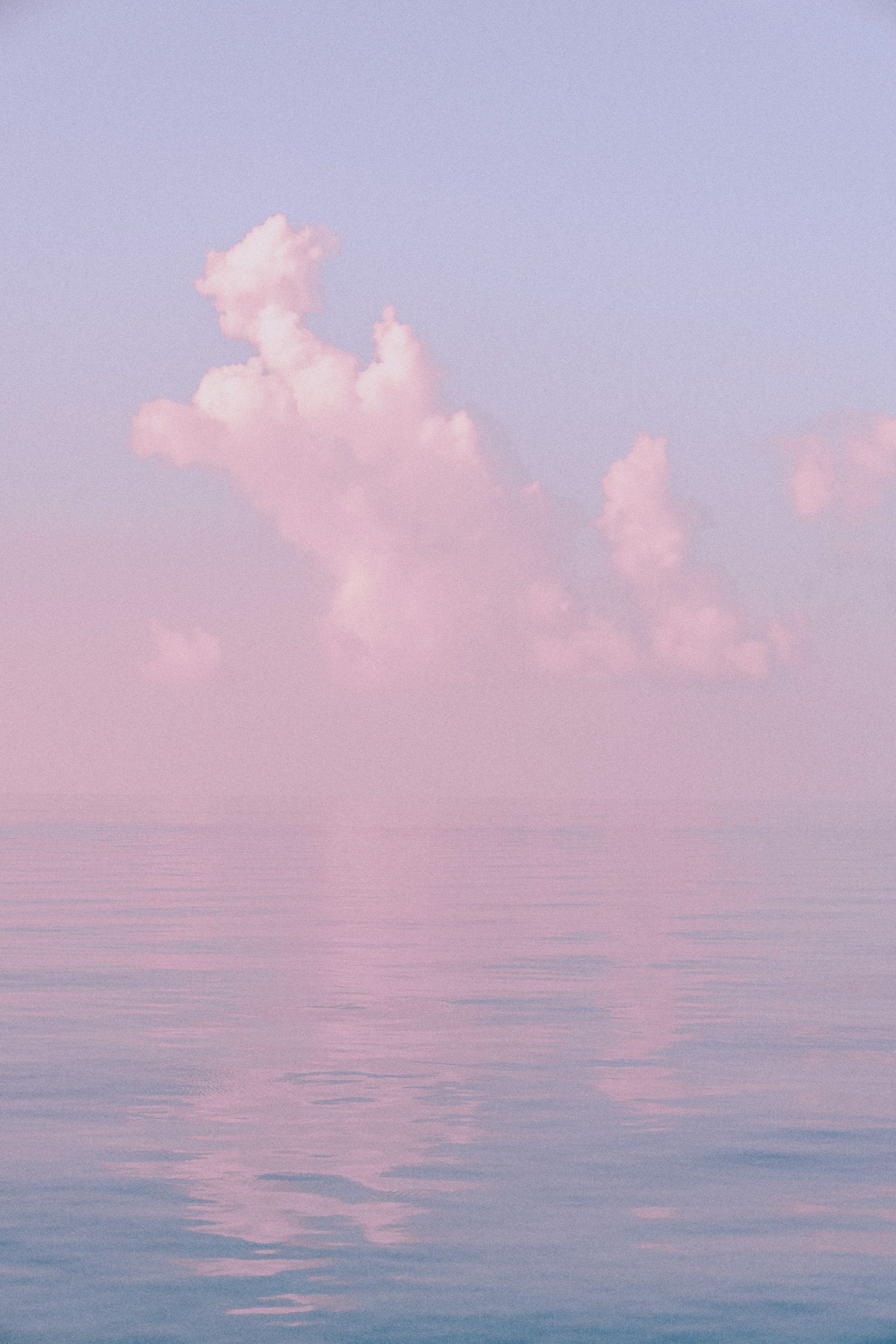 Pink and lilac clouds over still water at dusk